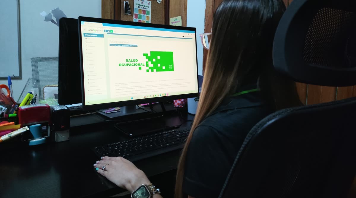 Persona frente a una computadora con el curso de Salud ocupacional abierto en el aula virtual de Academia Aprende.