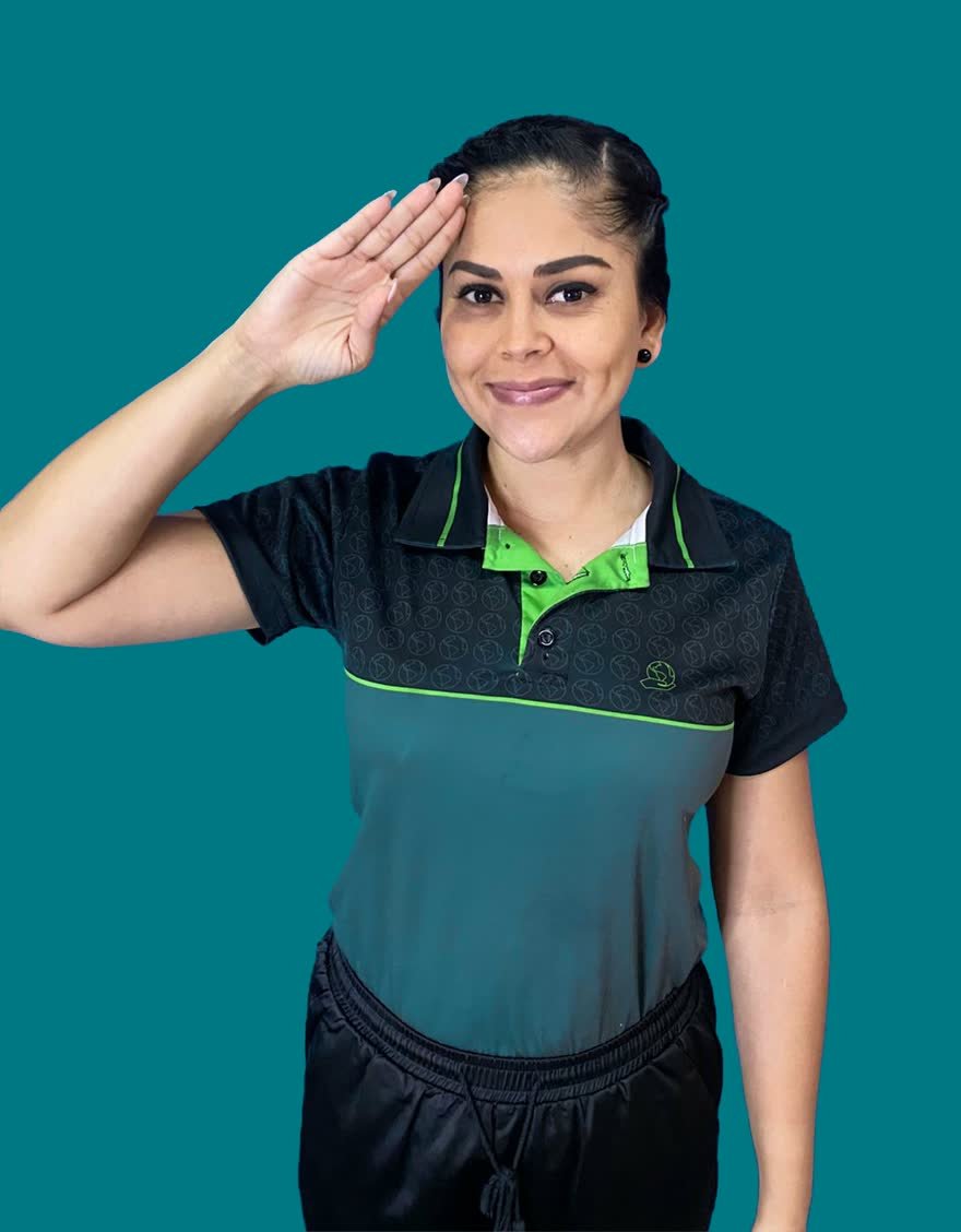 Profesora de LESCO de Academia Aprende, en uniforme, haciendo una seña con la mano frente a un fondo azul.